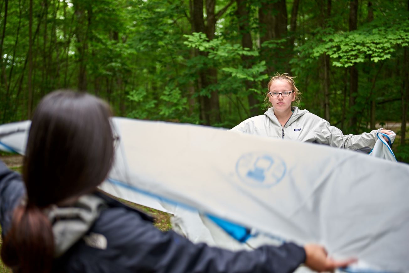 Two people setting up a tent