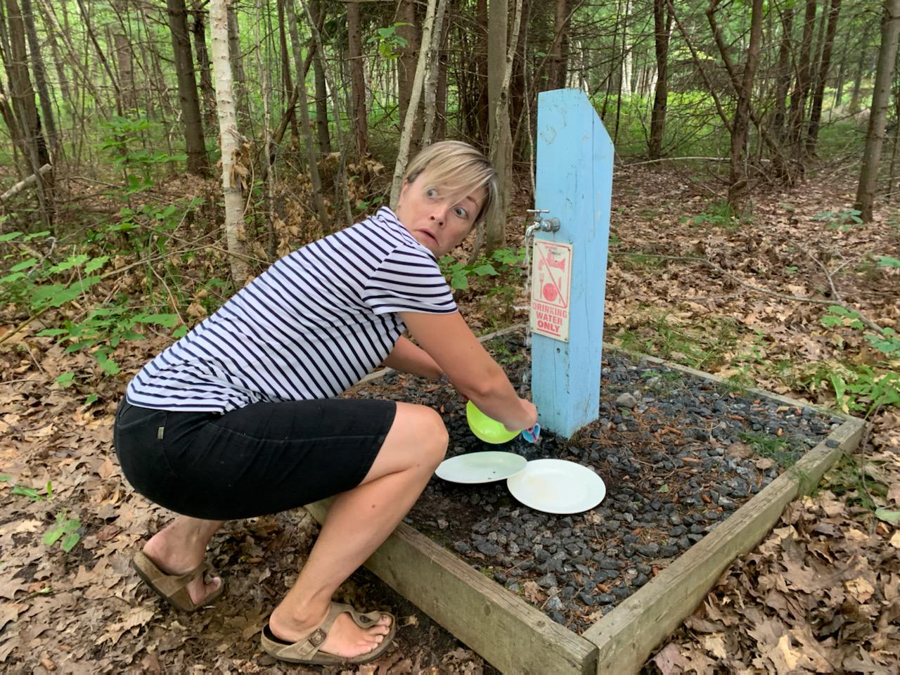 camper washing dishes under water tap