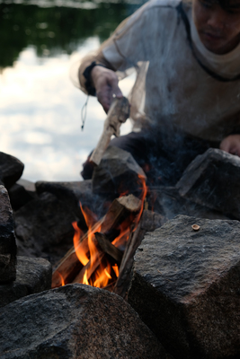 person with bug net tending to campfire