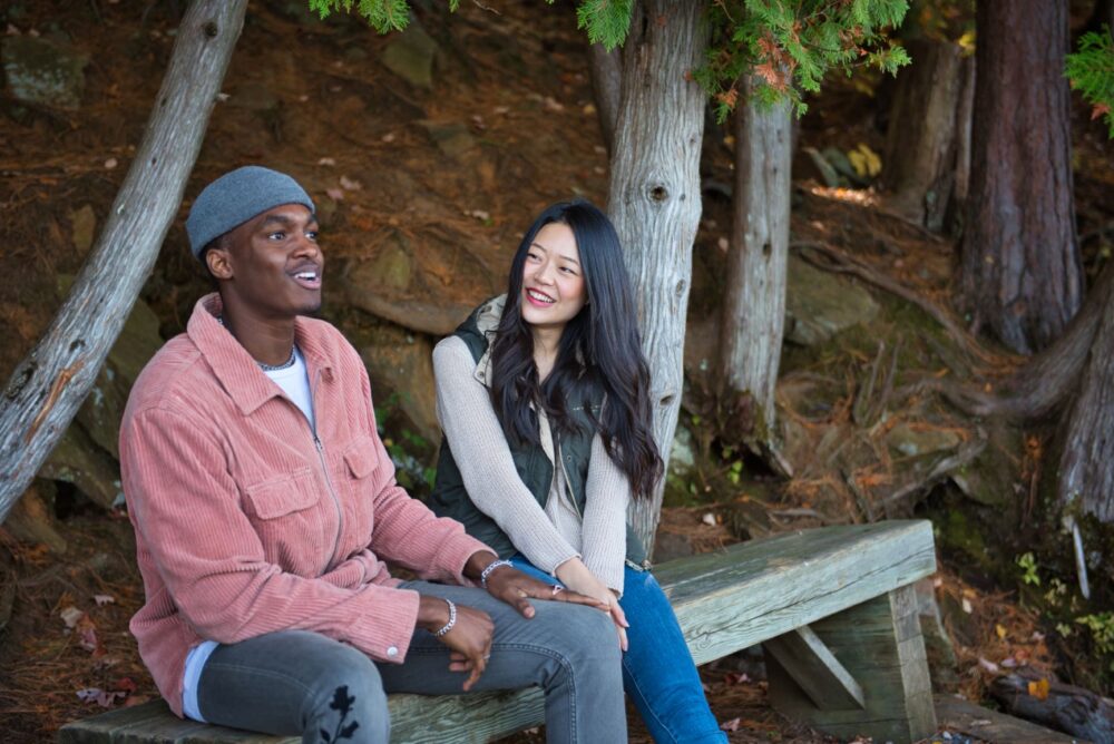 Couple sitting in bench in forest with cedar trees