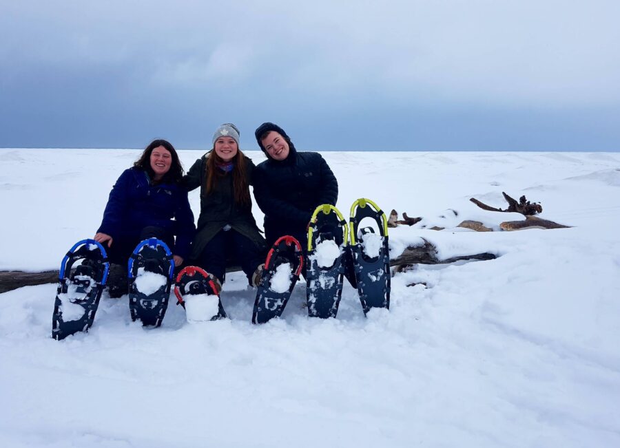 Group of 3 friends taking a break from snowshoeing