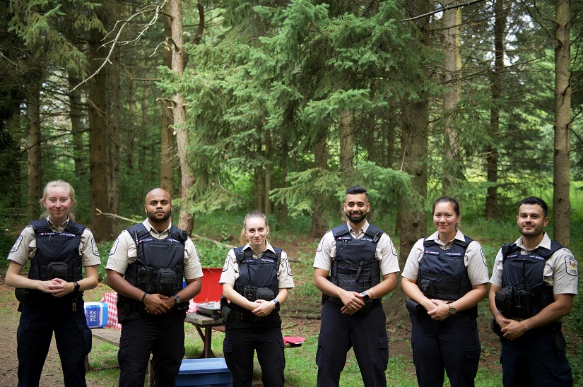 A group of park wardens standing in a line looking into the camera on a campsite