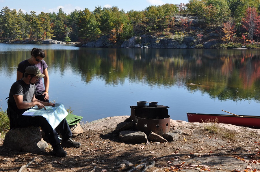 Couple planning their route with a map beside the lake.