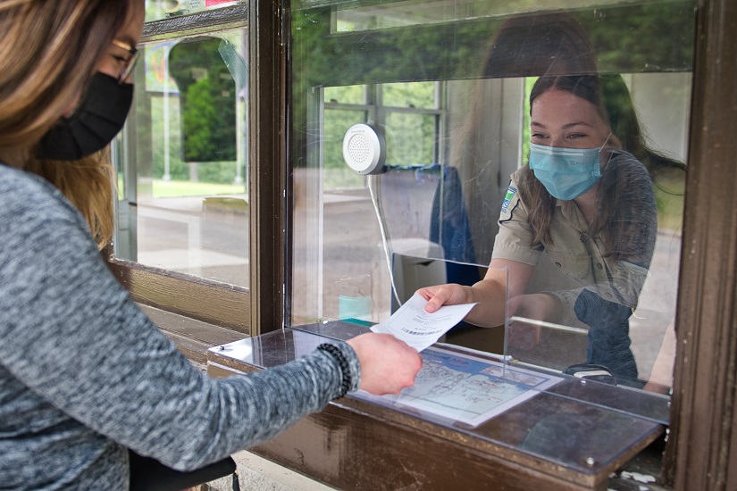 A masked visitor obtains their vehicle permit at Emily Provincial Park's gatehouse. 