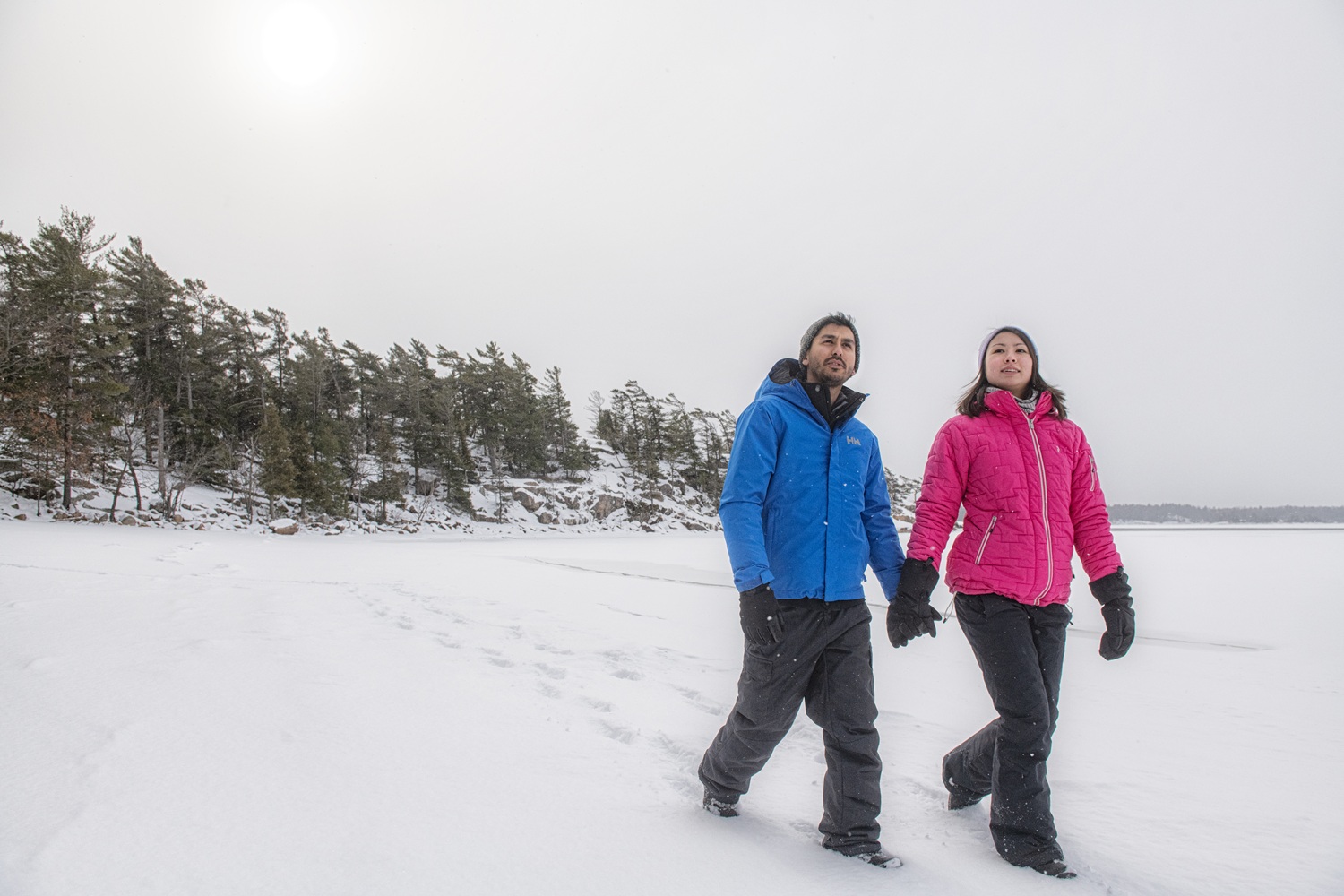 couple holding hands hiking through snow