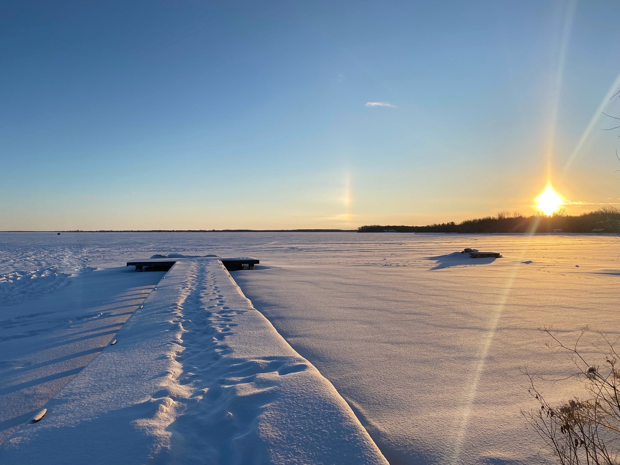 frozen lake covered in snow. Dock in foreground