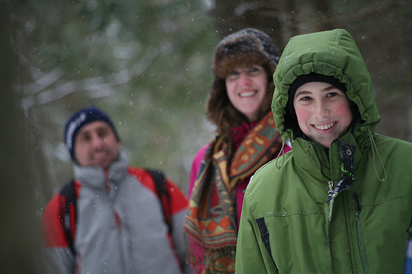 un groupe de trois personnes en vêtements d’hiver souriant à l’objectif