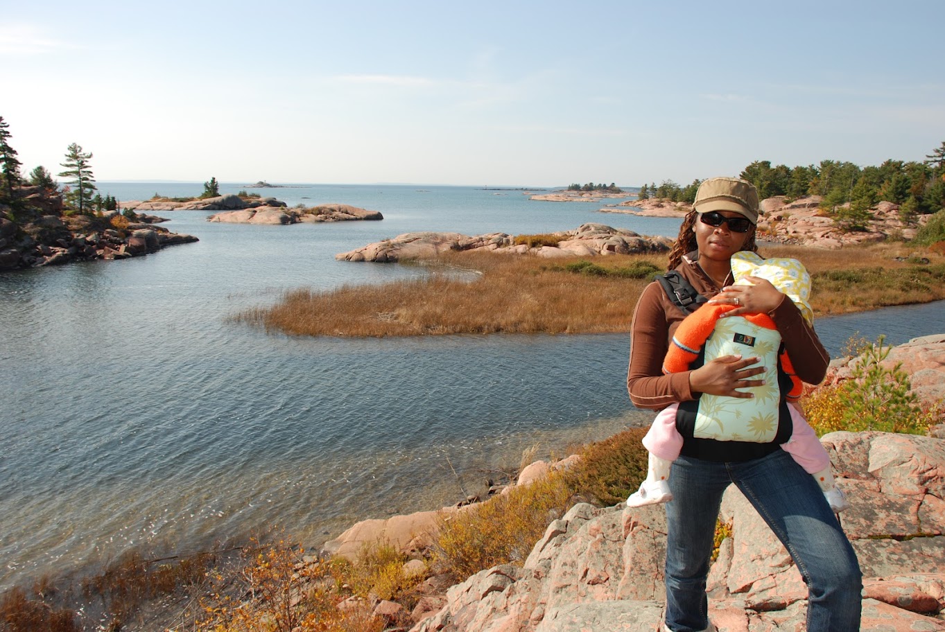 mother holding baby in sling looking out at lake