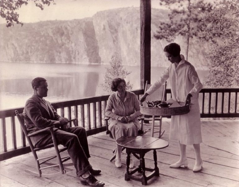 Black and white photo of guests seated on the porch of the inn