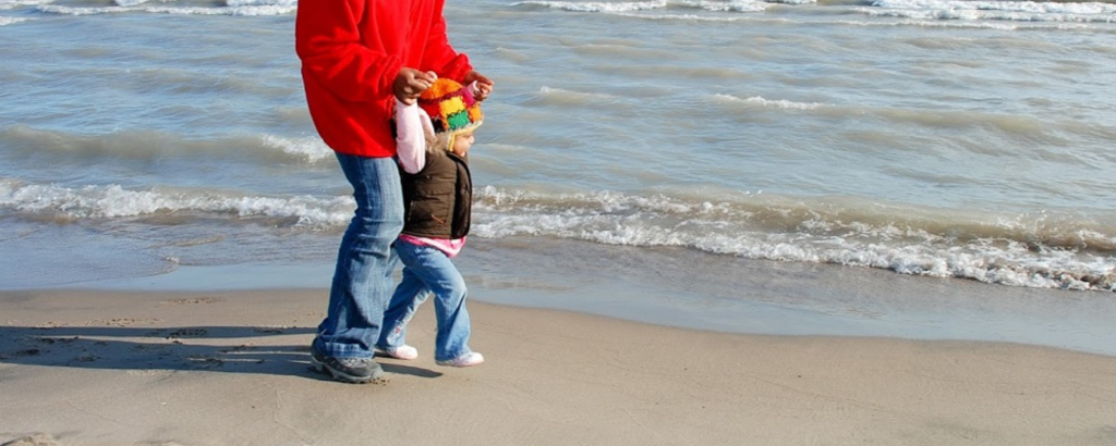 Claire and her child walking on a beach in the fall
