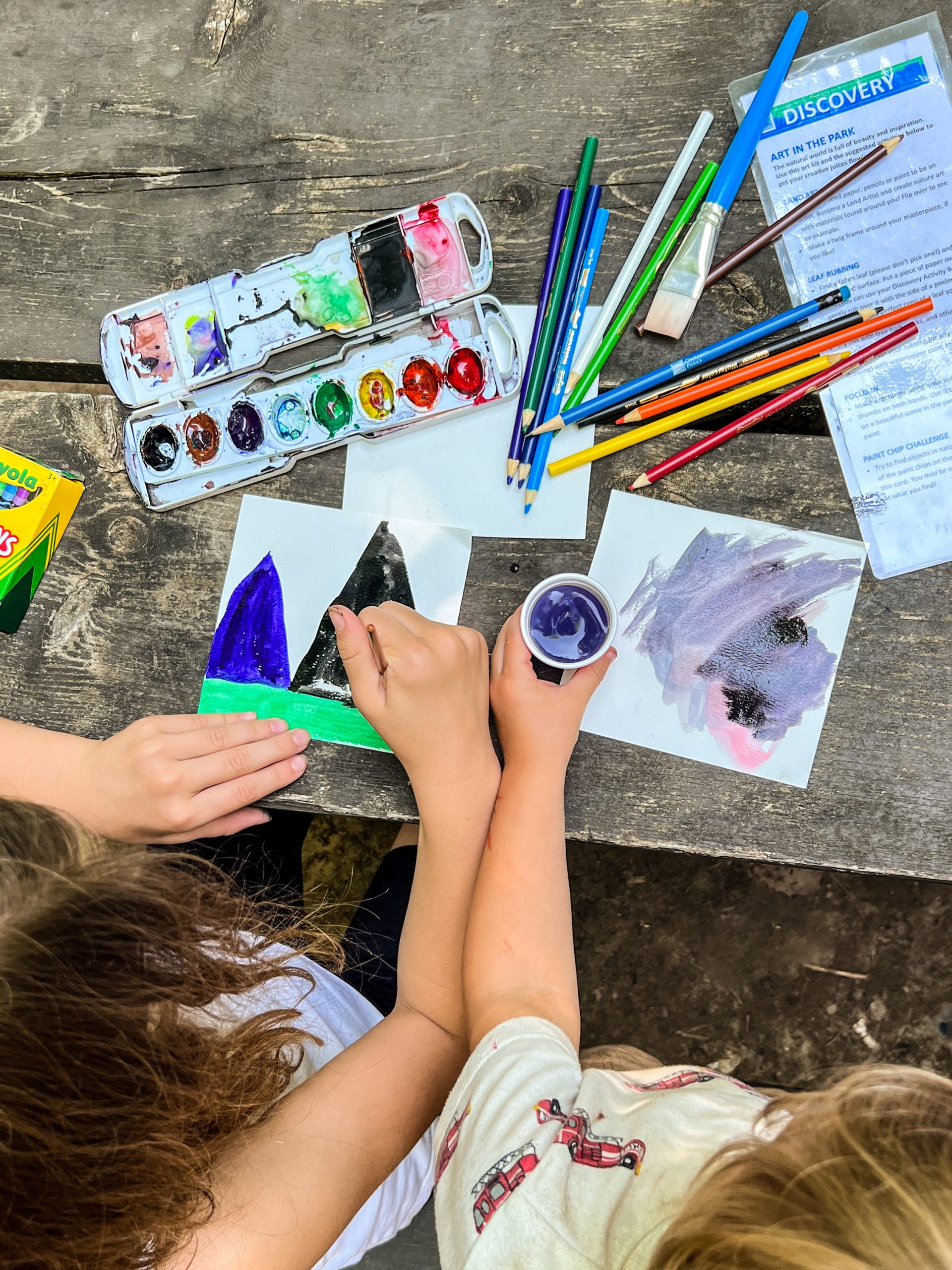 A view of art supplies and paintings on a picnic table