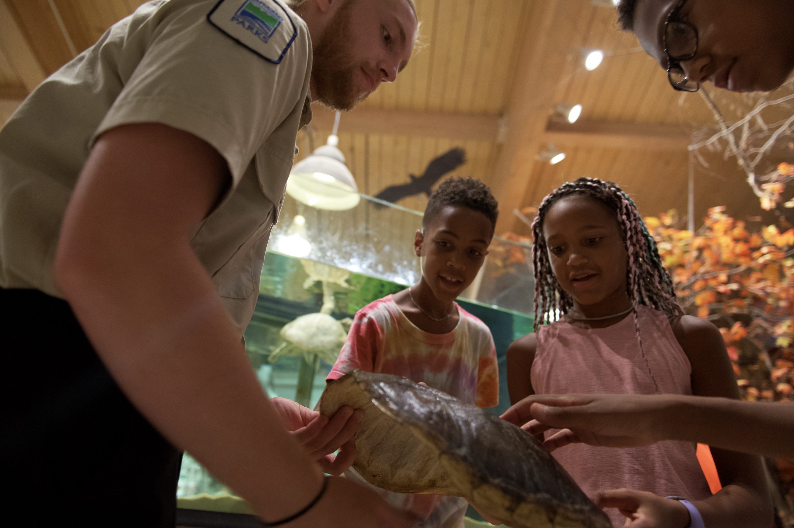 A Discovery ranger shows a turtle shell to a family inside a Visitor Centre