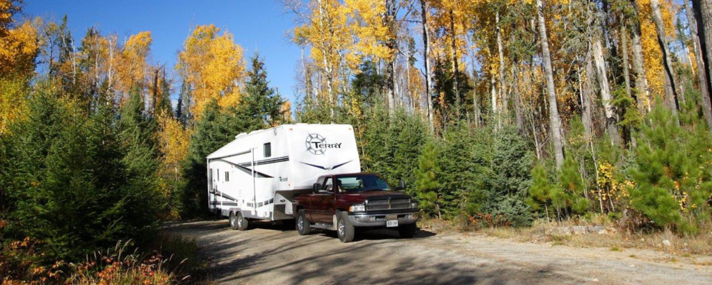 Truck pulling RV in fall forest