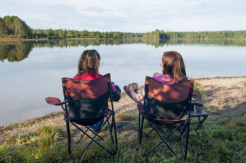 two people sitting on chairs looking out at water