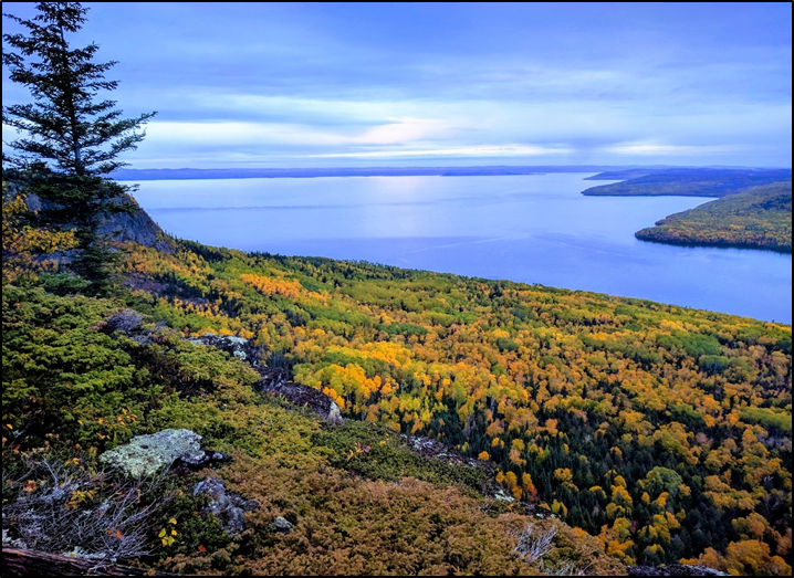 Rocky outlook looking out over a forest in fall colours and a large lake.