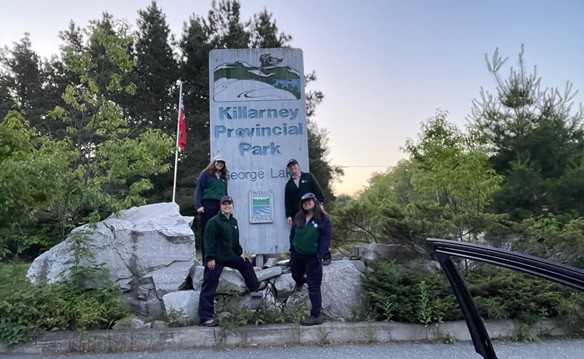 staff standing beside sign