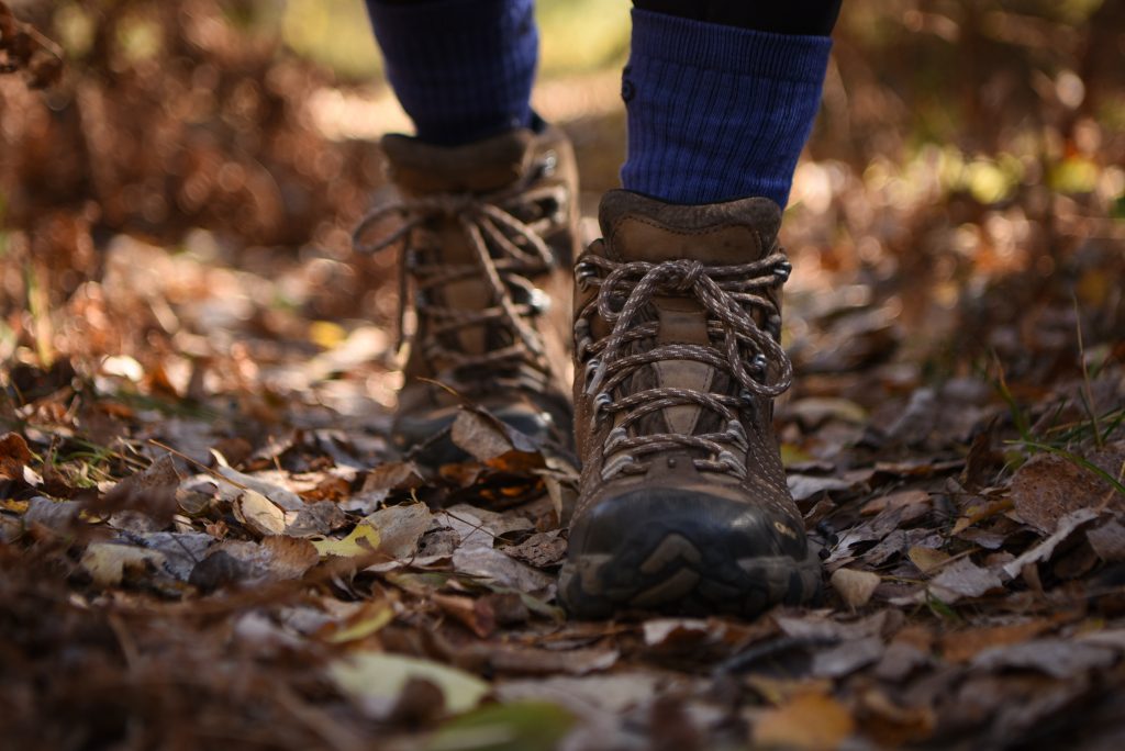 close up of person's boots hiking through fallen leaves