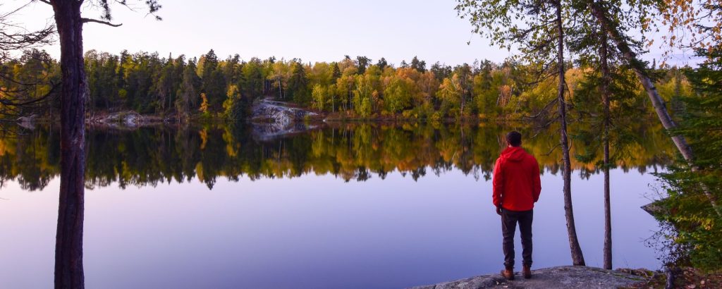 hiker lookout out at lake with fall colours reflected in water