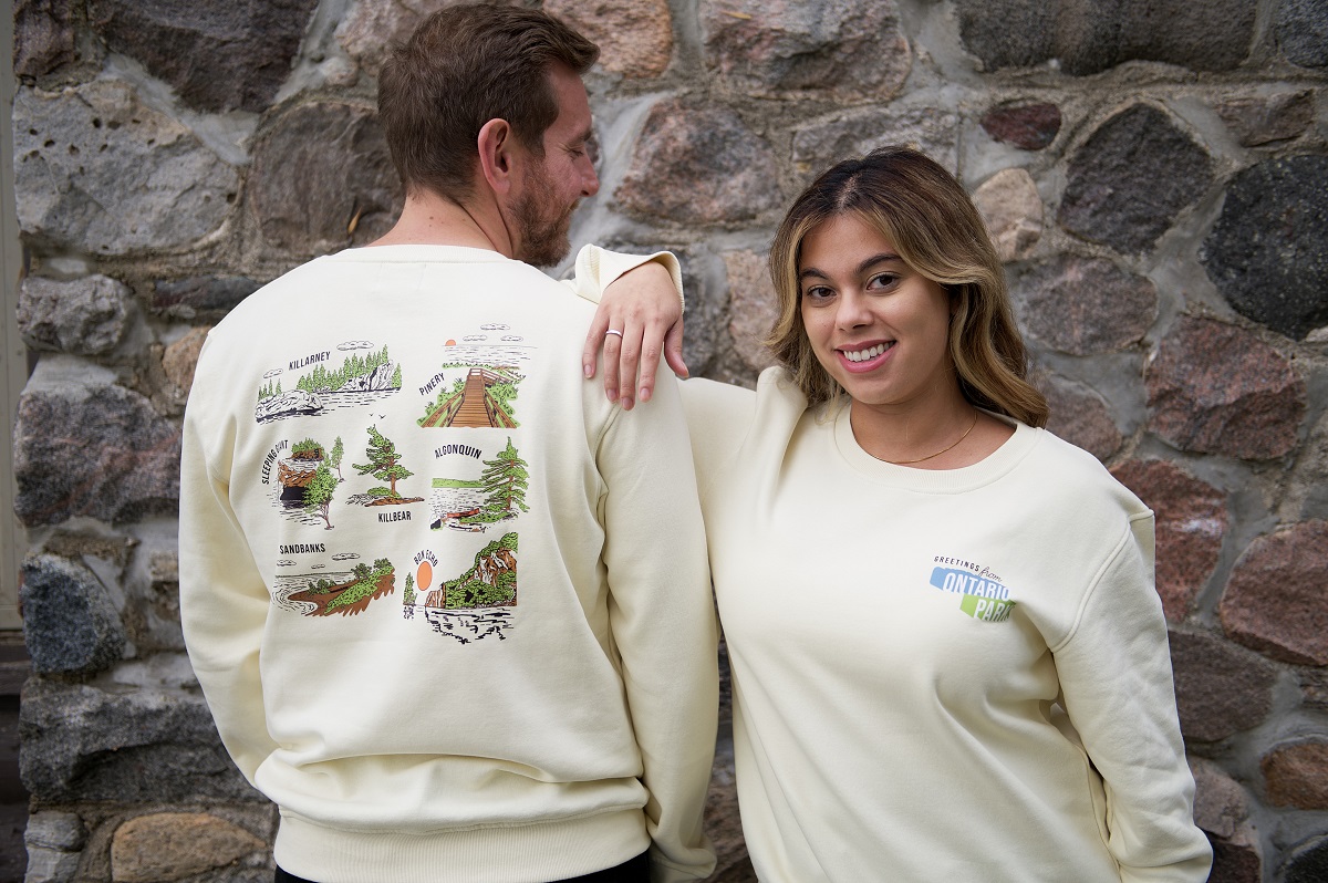 two people wearing cream sweatshirts with nostalgic park graphics