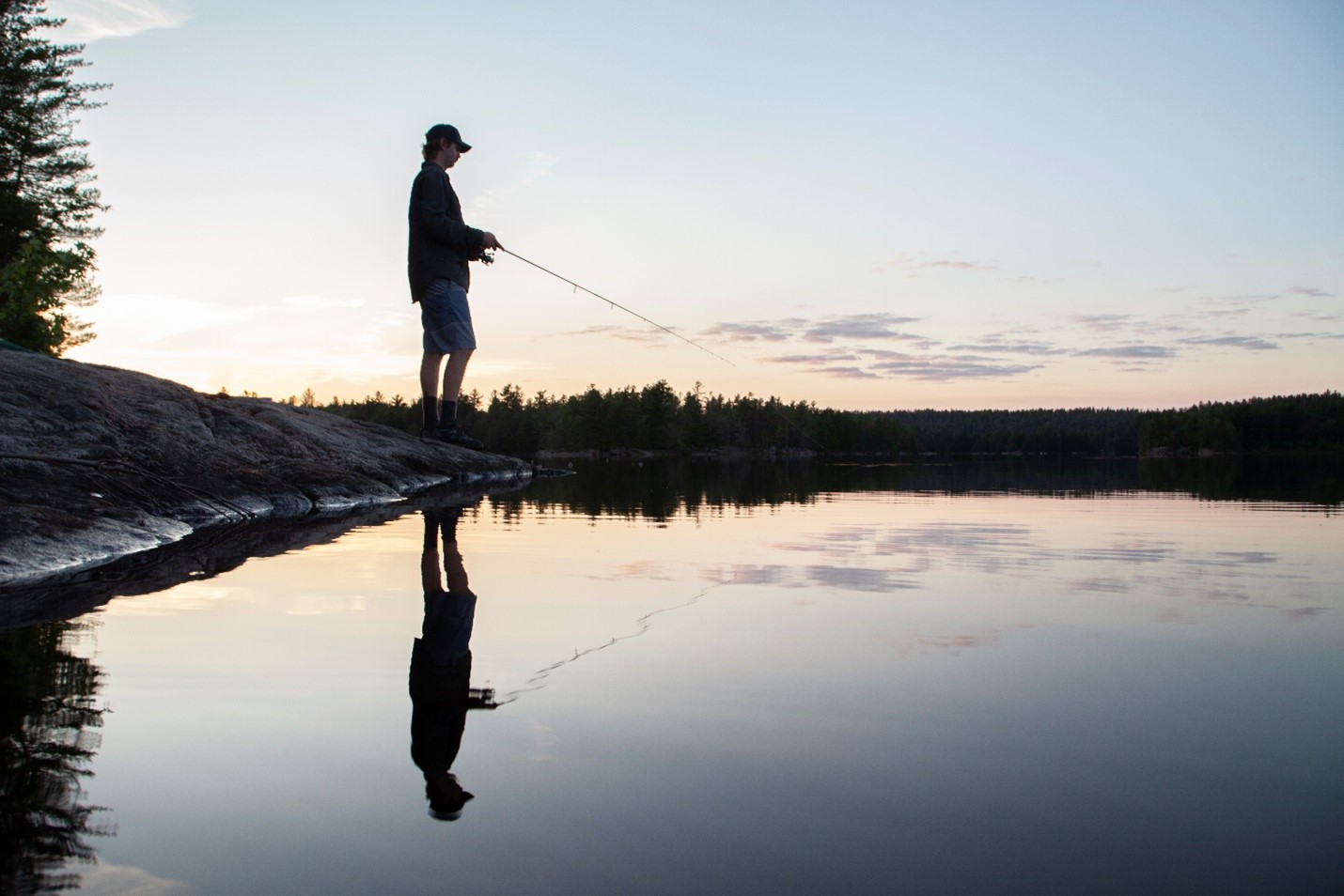 A person fishing in a lake at sunset