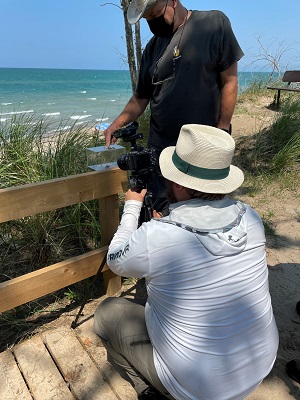 person filming lake with camera