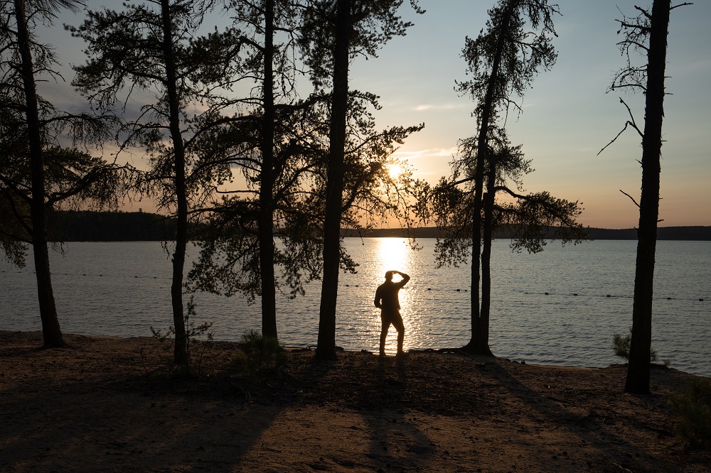 silhouette of a person looking over the beach / swim area at sunset