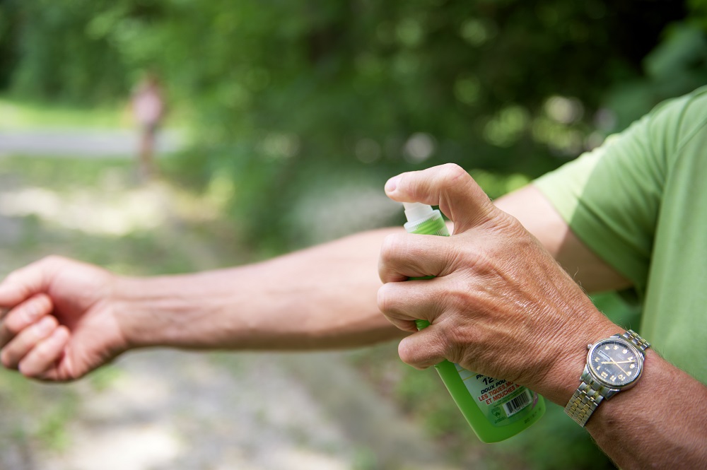 Man spraying bug spray on arm