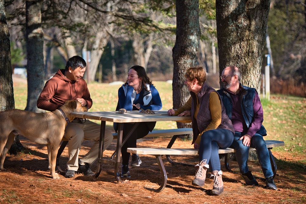 A family sitting around picnic table with dog