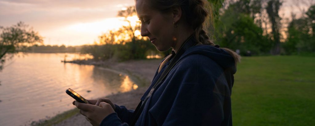 woman looking at phone at sunset
