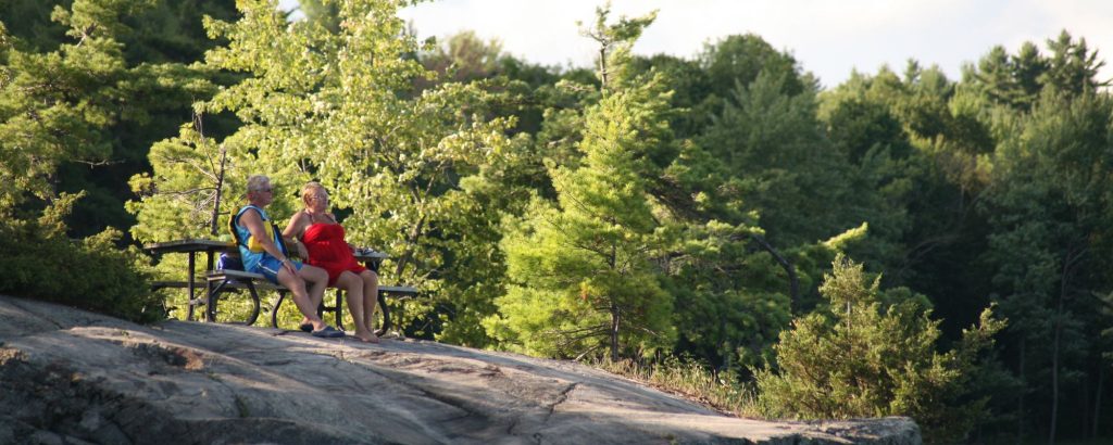 couple sitting at picnic table on rocky shore