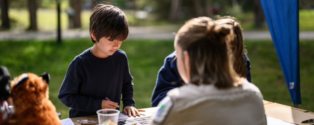 staff sitting at explorations station, children looking at items on table