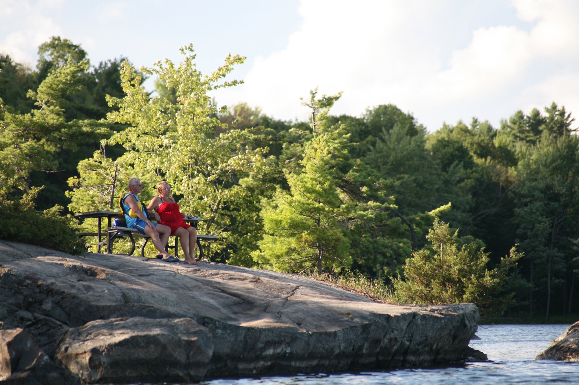 senior couple sitting on picnic table on rocky shore