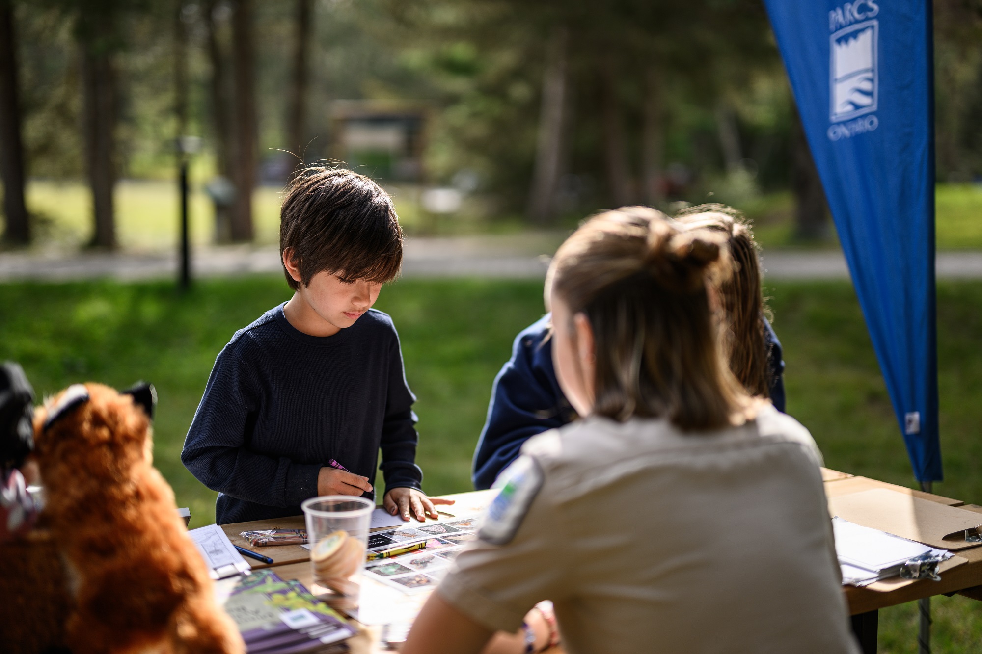 staff sitting at explorations station, children looking at items on table