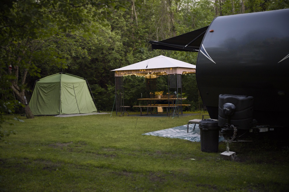 campsite with trailer, sun shade, and tent