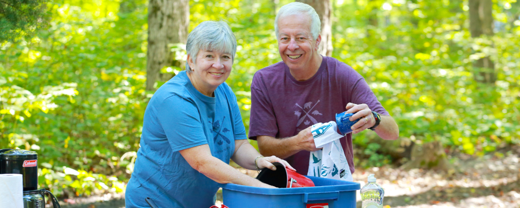 Couple washing dishes on picnic table