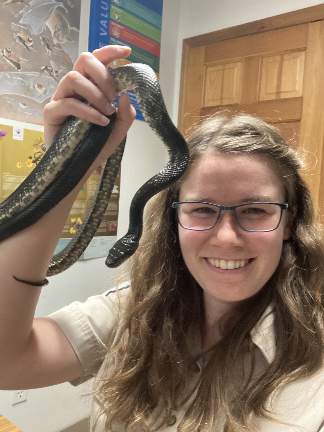 A person holding a thin grey snake and smiling at the camera