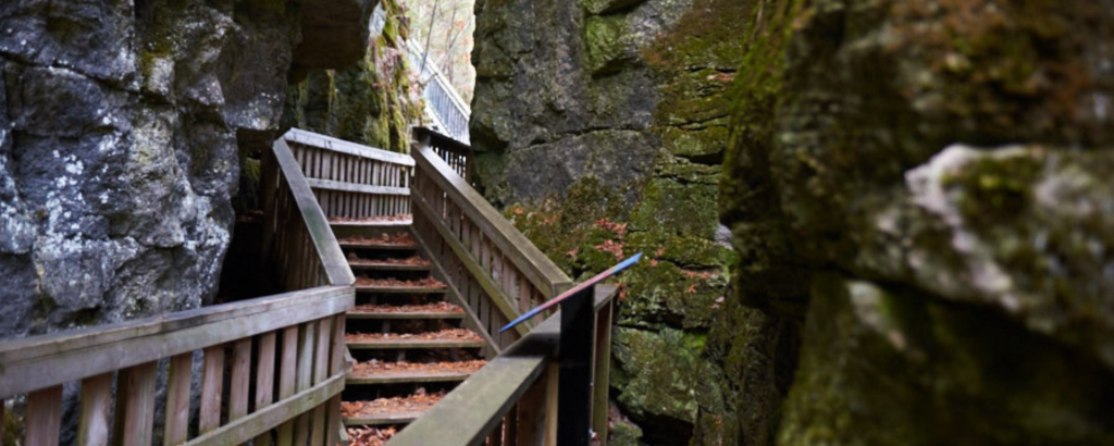 A wooden staircase with railings through a crack in a rocky mountain