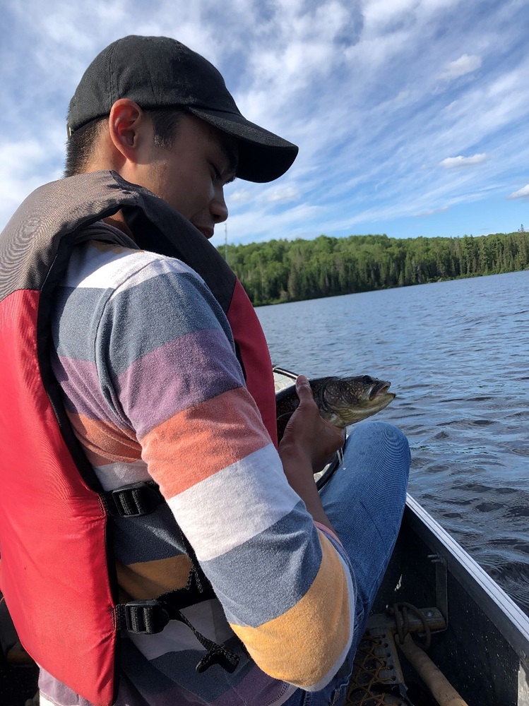 man holding fish in canoe