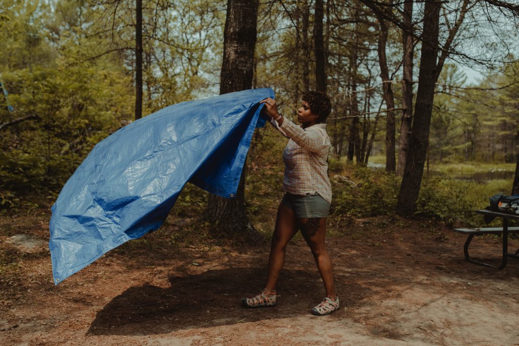 woman laying out tarp on campsite