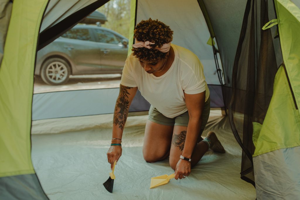 woman sweeping up inside tent