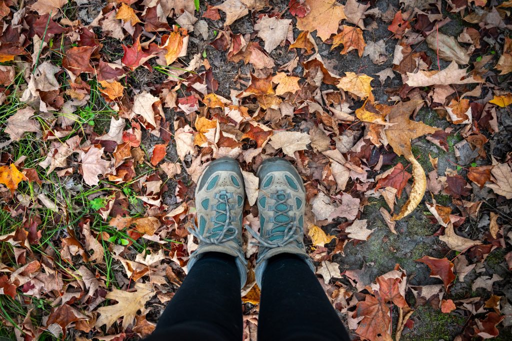 De chaussures de randonnée sur le sol d’une forêt recouvert de feuilles mortes