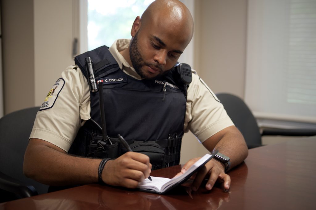 park warden sitting at desk taking notes