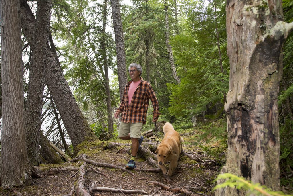 man walking dog through forest