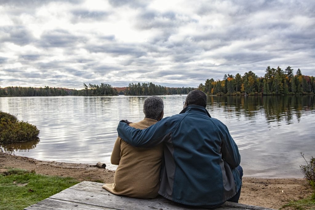 couple sitting on bench looking out at lake