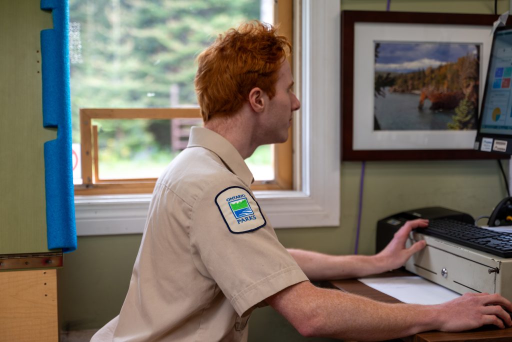 staff sitting inside front gate, working on computer