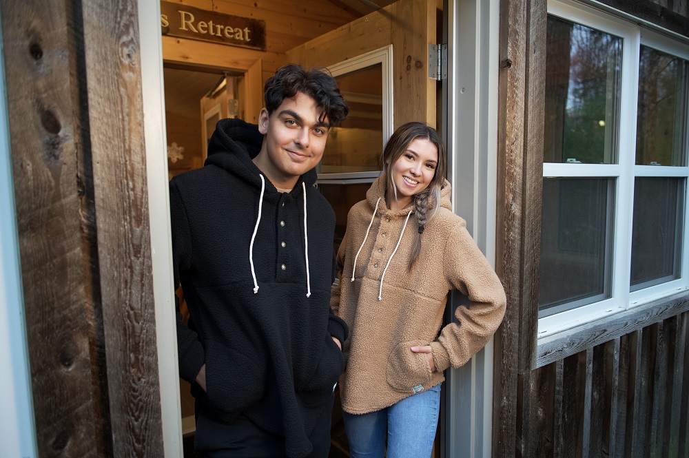 two models standing in doorframe of cabin