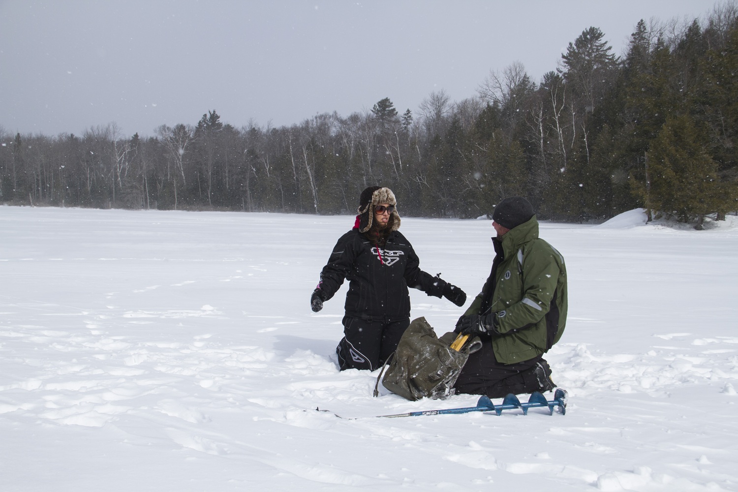 two people ice fishing on snowy lake