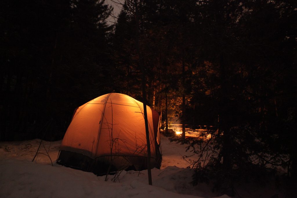 lit orange tent at night on snowy site
