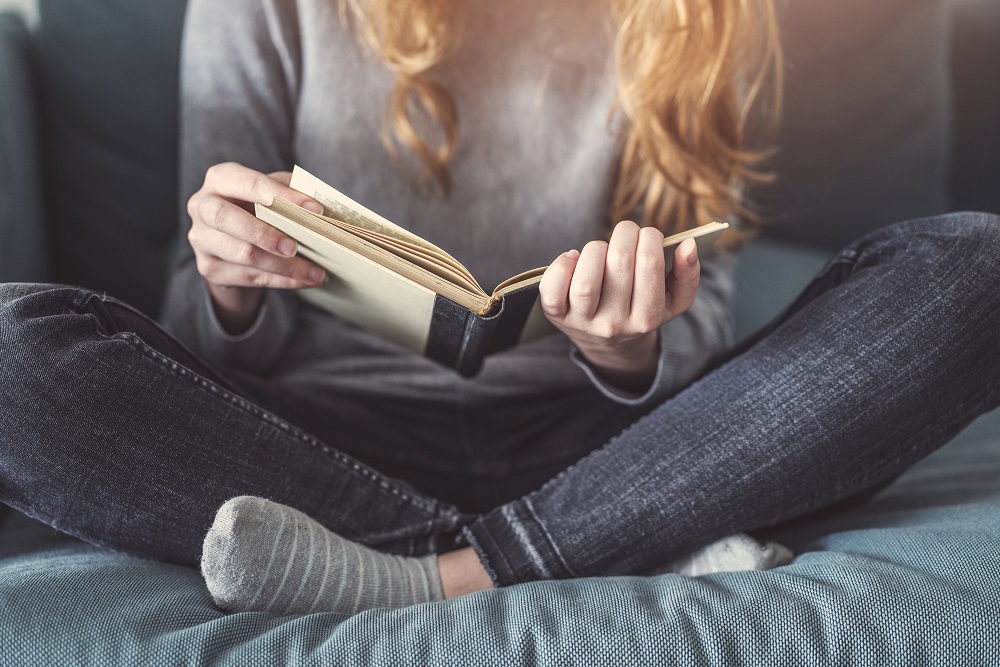 person with crossed legs reading book