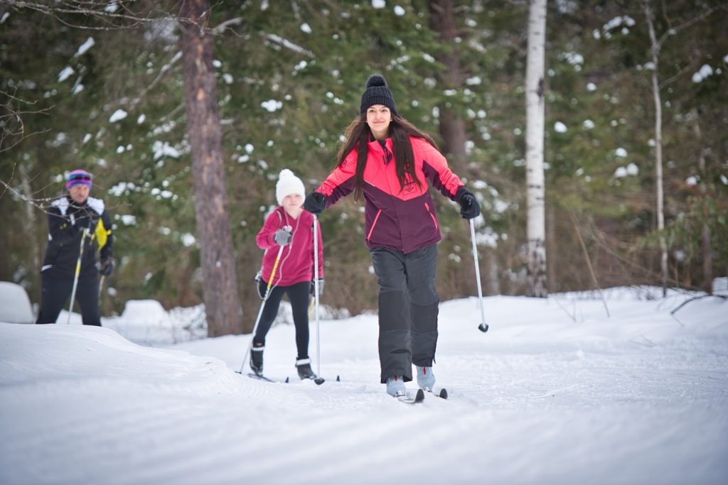 family of cross-country skiers on trail in forest